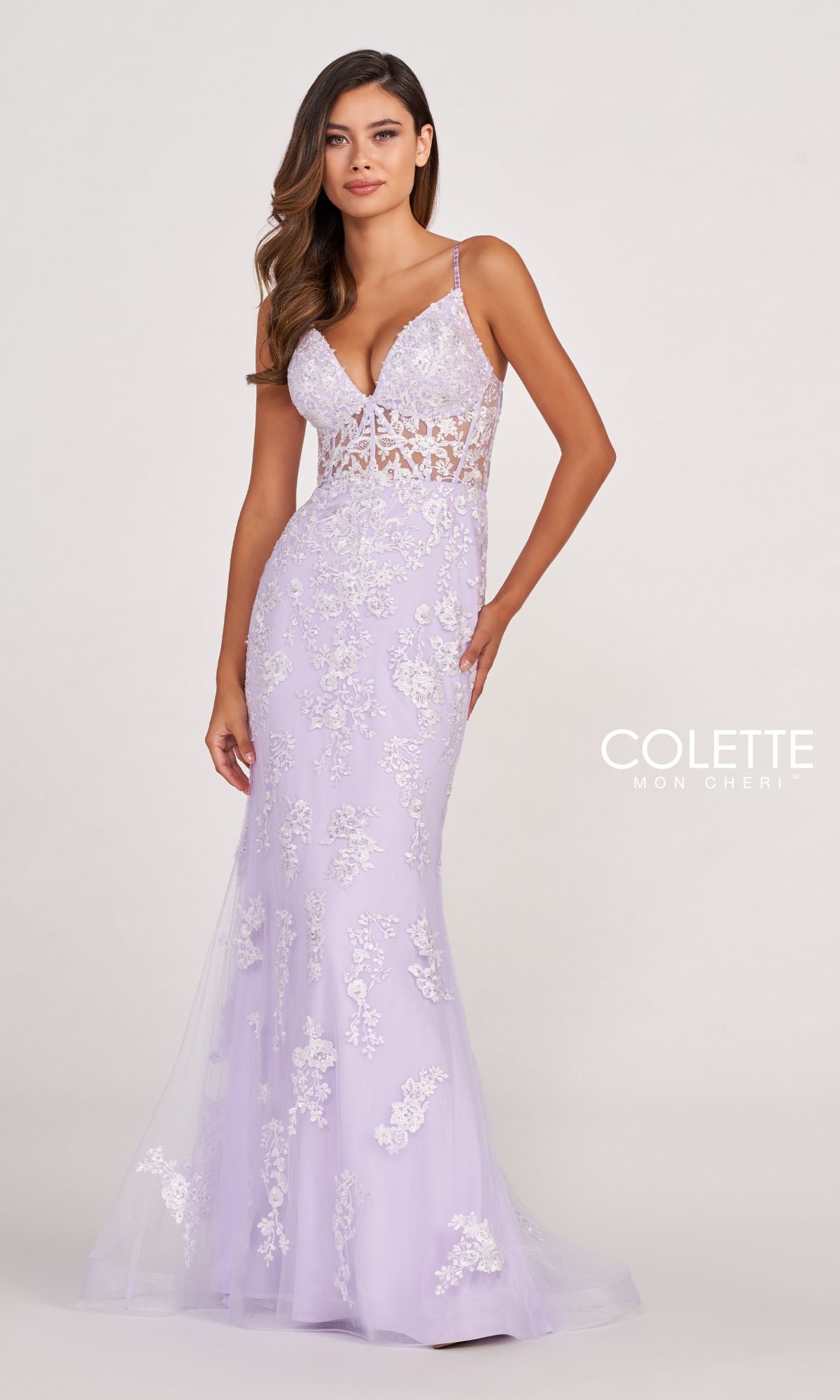 A woman poses against a plain background wearing the Colette Beaded-Lace Long Prom Dress with a corset, featuring floral lace details, sheer bodice panels, thin straps, and a light purple floor-length design.